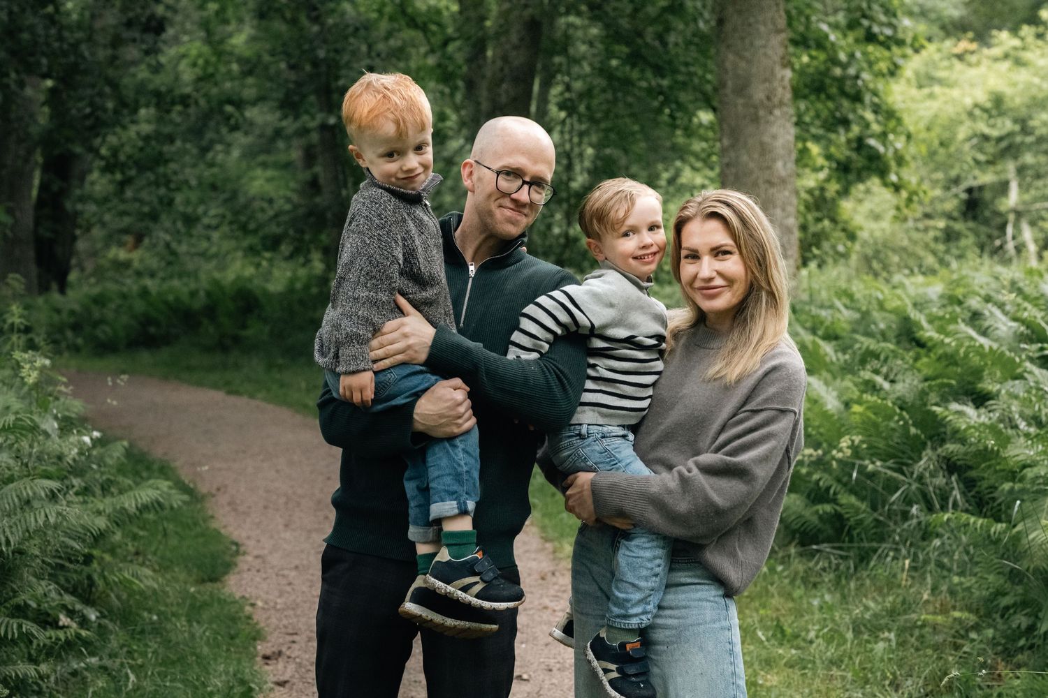 Family enjoying a lighthearted moment together in wooded park setting.