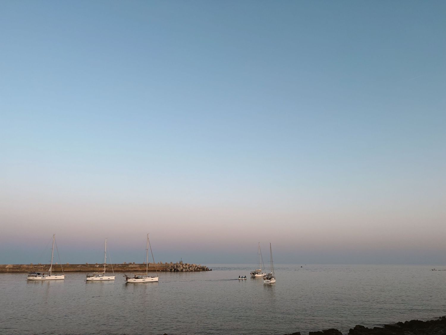Panoramic view of boats anchored in calm waters against a clear blue horizon.