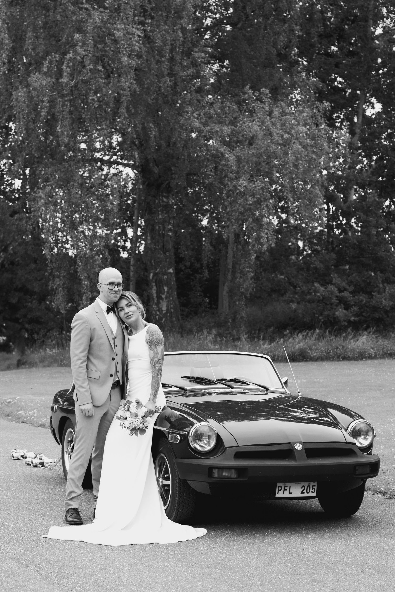 Black and white photo of elegant couple with vintage sports car.