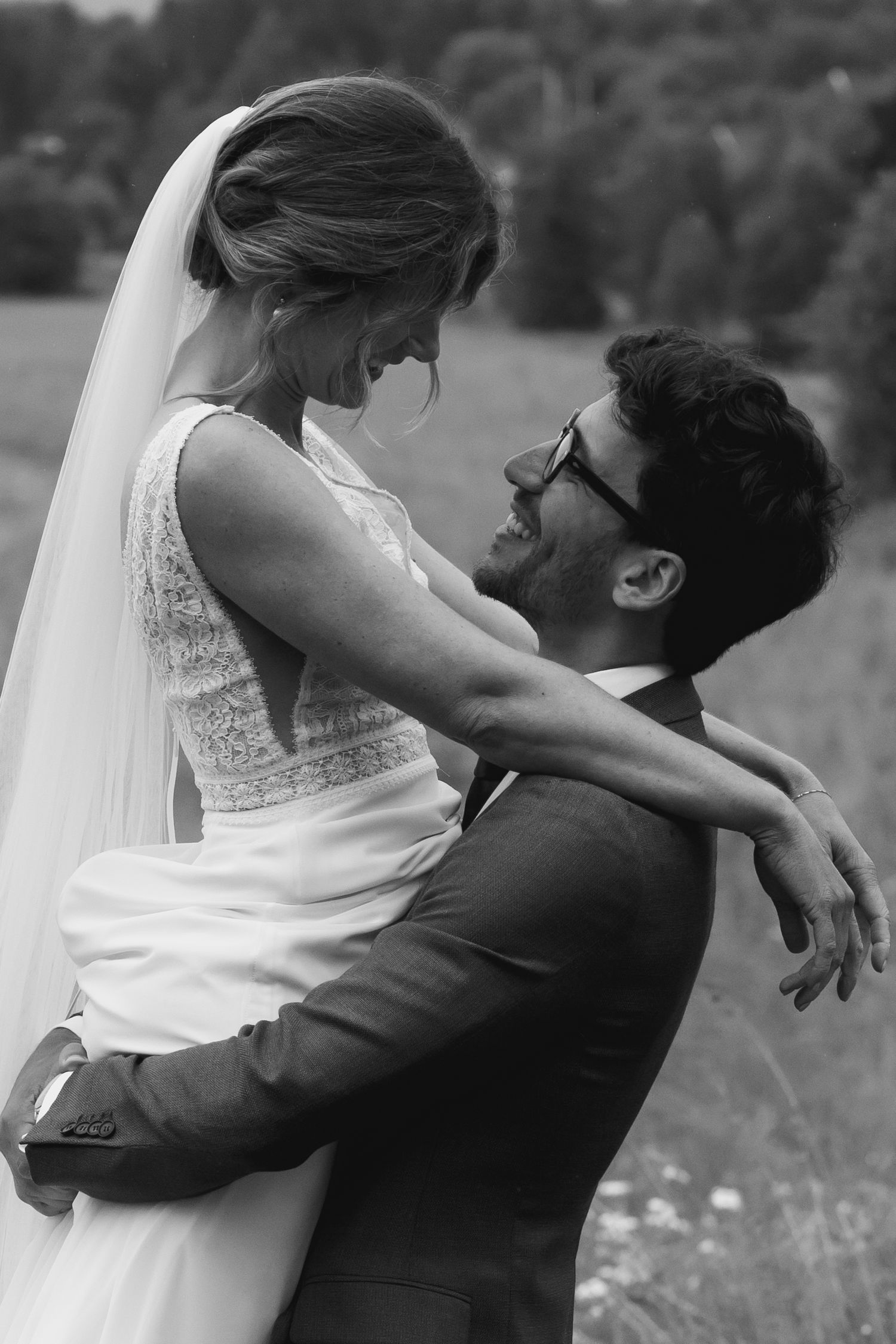 Black and white wedding photos showing romantic embraces in a meadow.