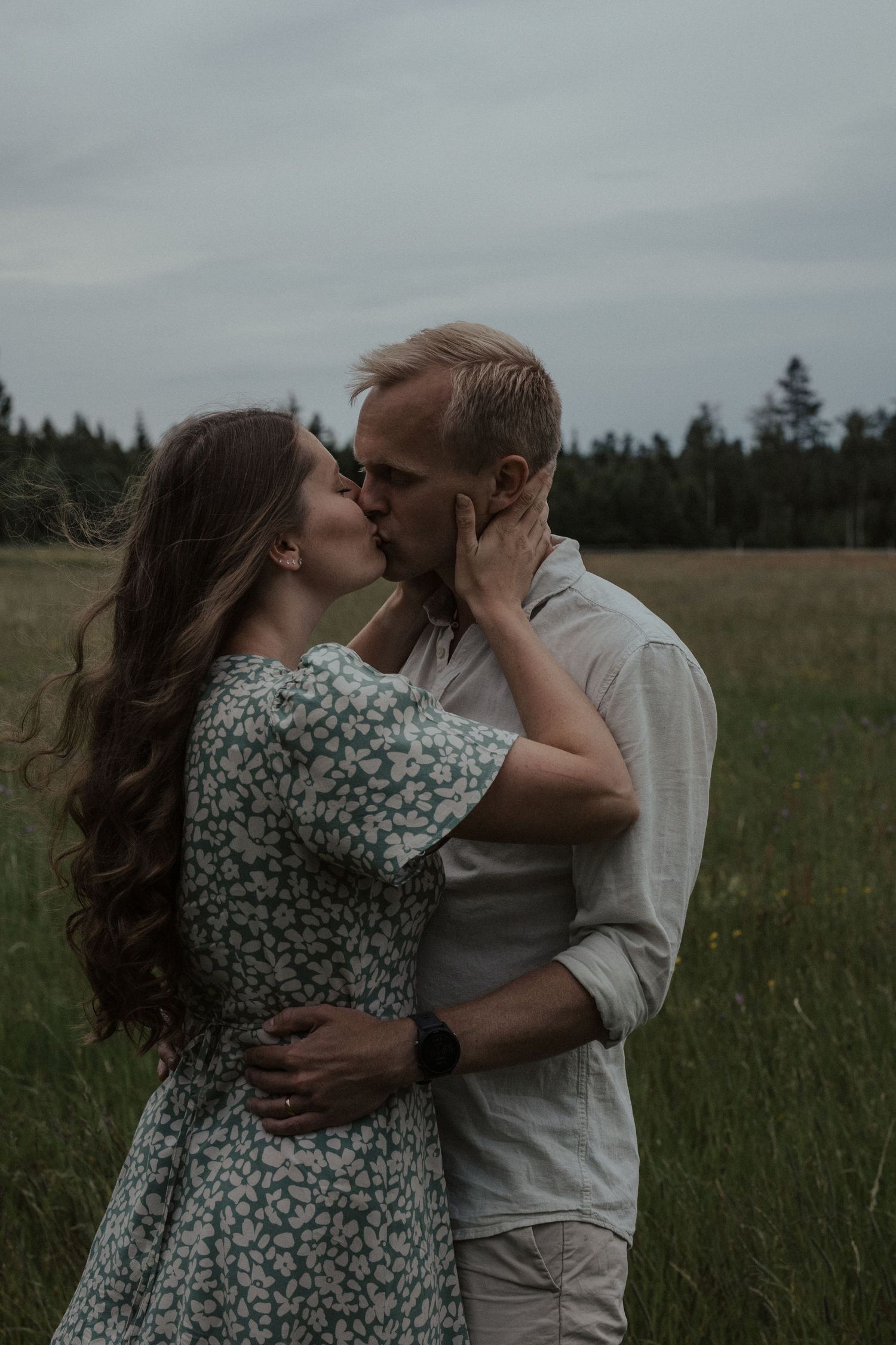 A tender embrace between a couple in a field during golden hour.