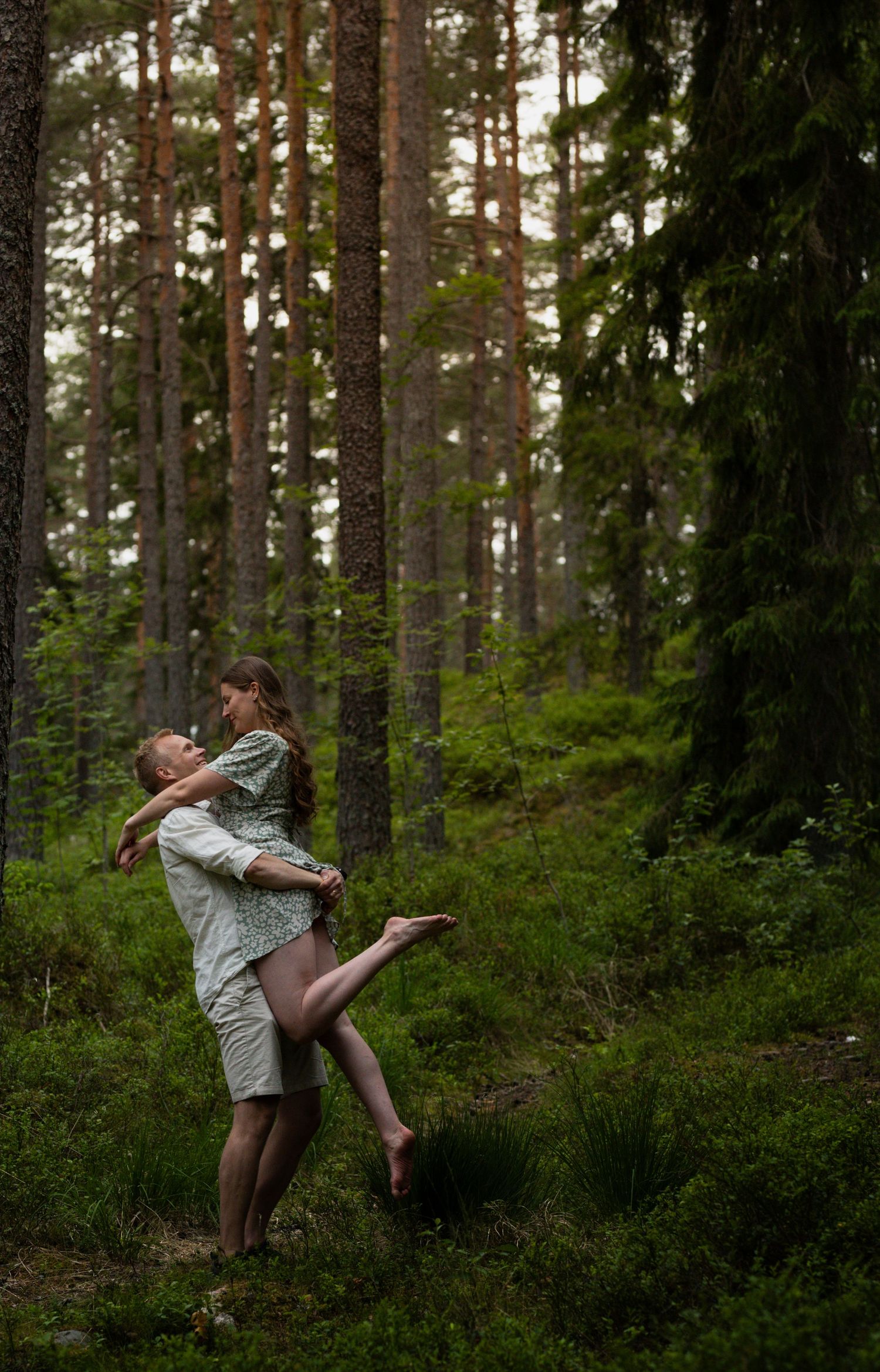 A couple sharing a playful moment in a forest setting.