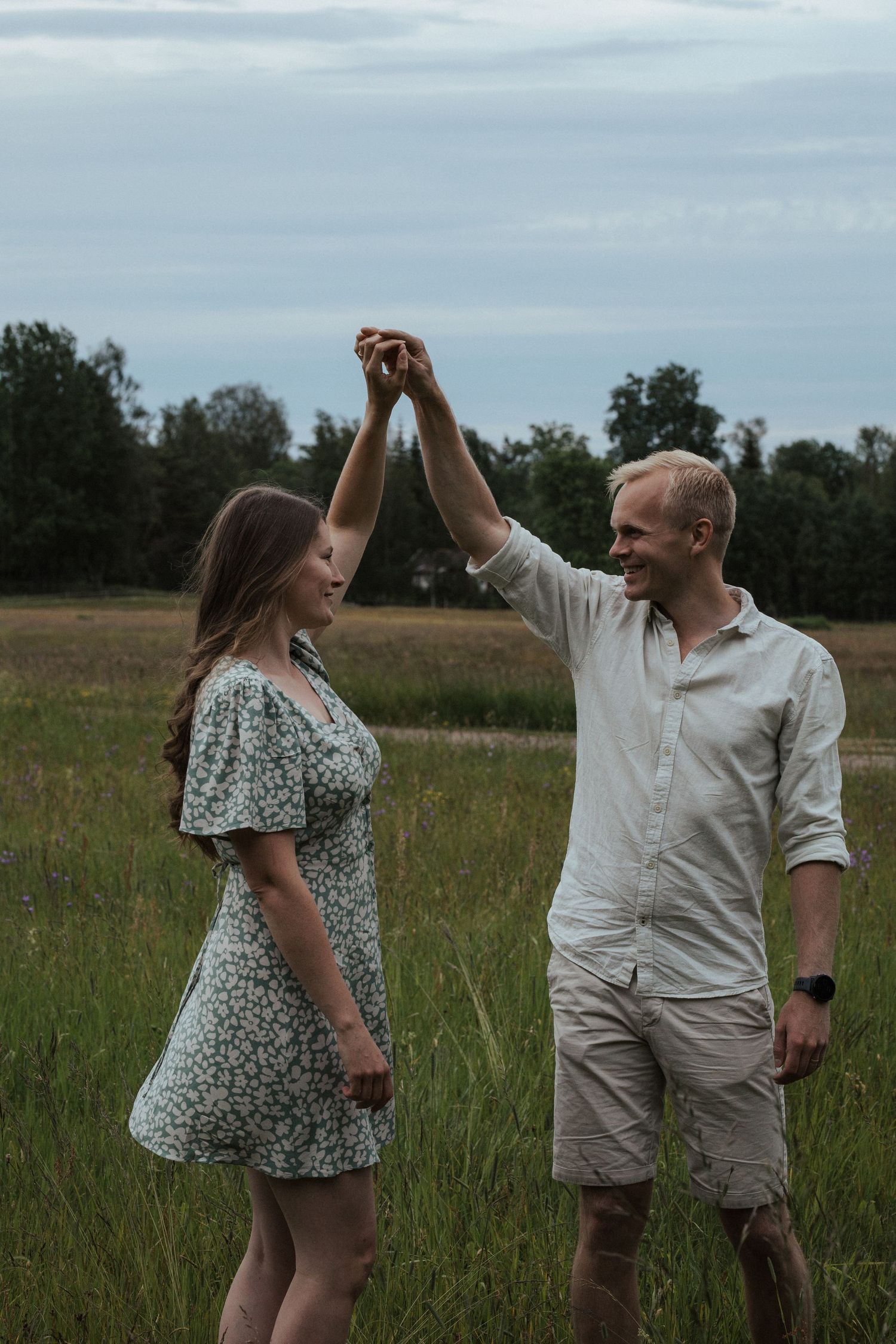 A couple dancing and twirling together in a sunlit meadow with wildflowers.