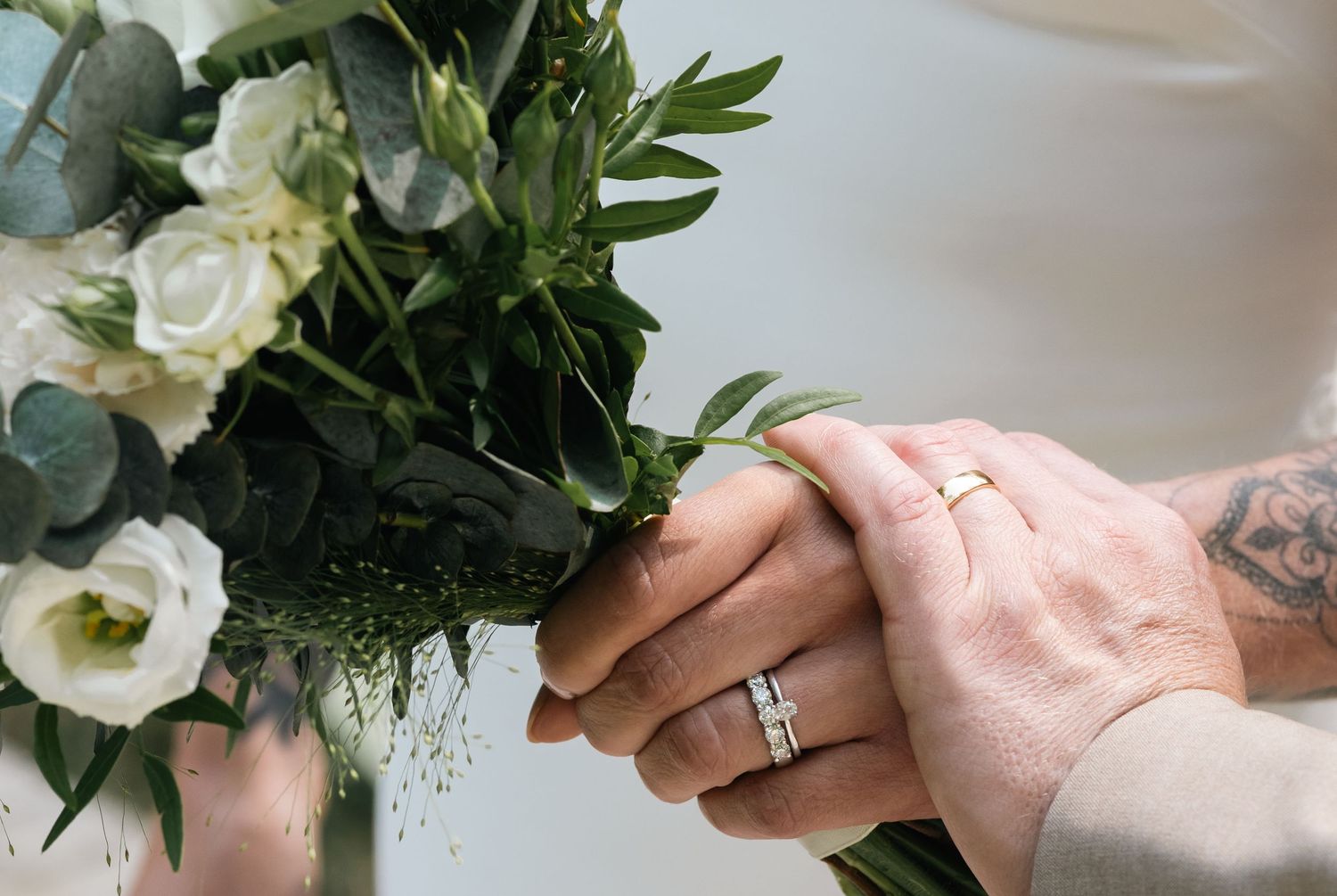 White and green wedding bouquet held in hands with delicate floral arrangement.
