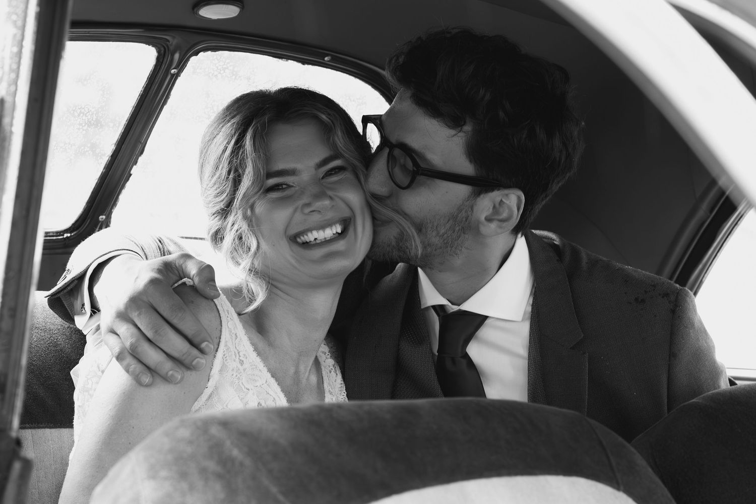 A series of candid black and white wedding photos taken inside a car.
