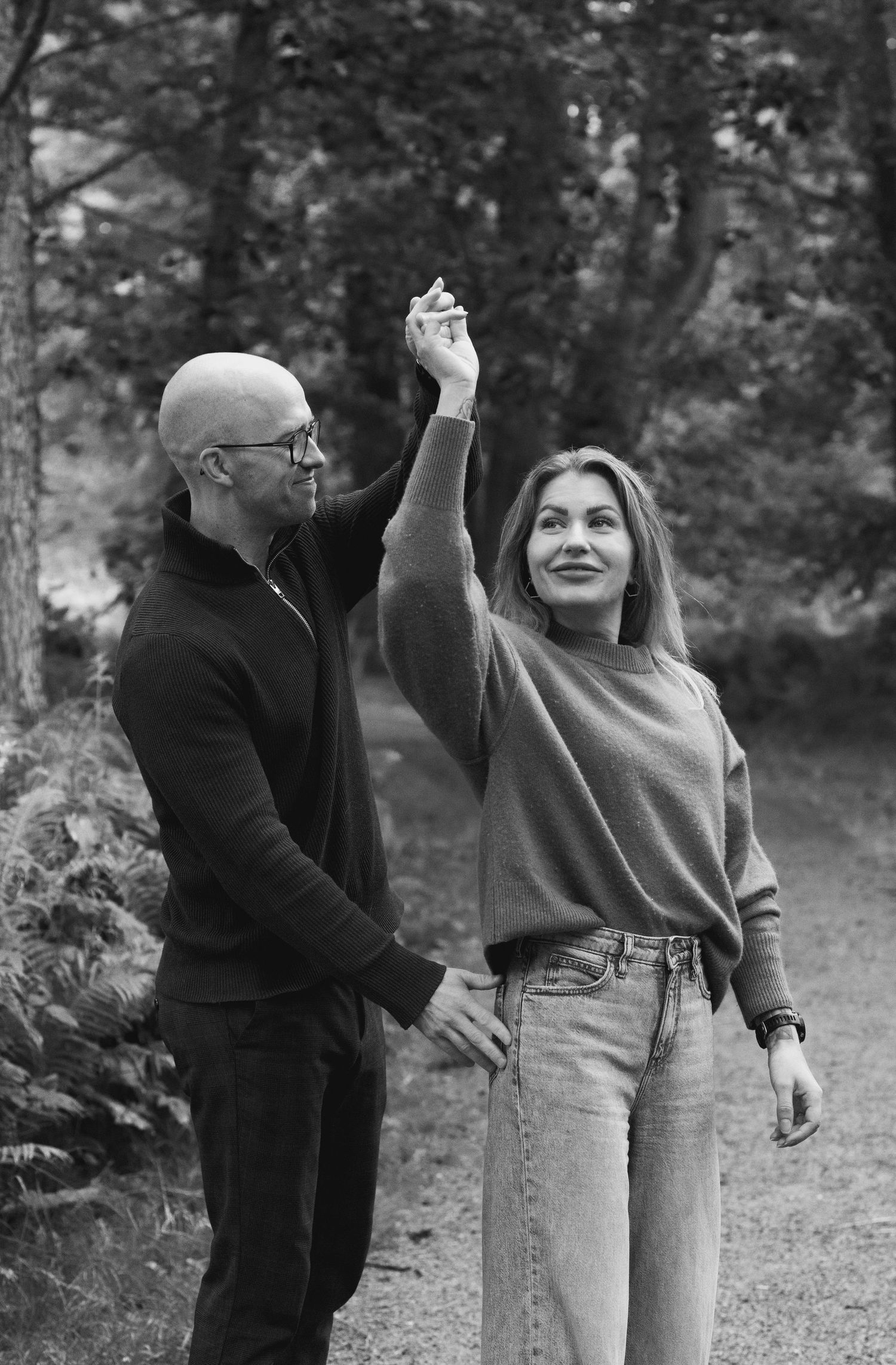 People enjoying playful moments together on a forest path in black and white.