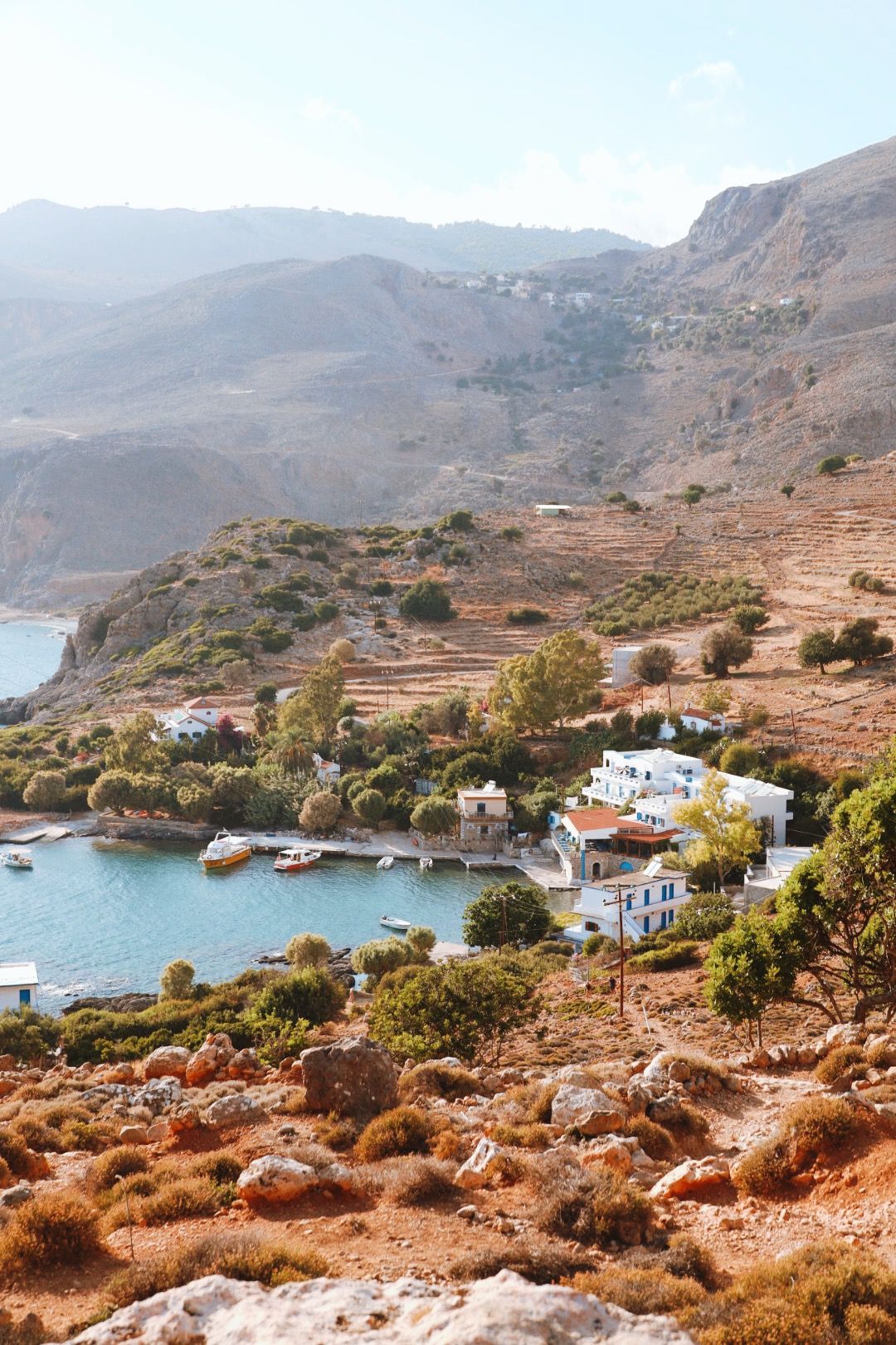 Panoramic view of a seaside harbor with traditional white houses and small boats along the Mediterranean coastline.