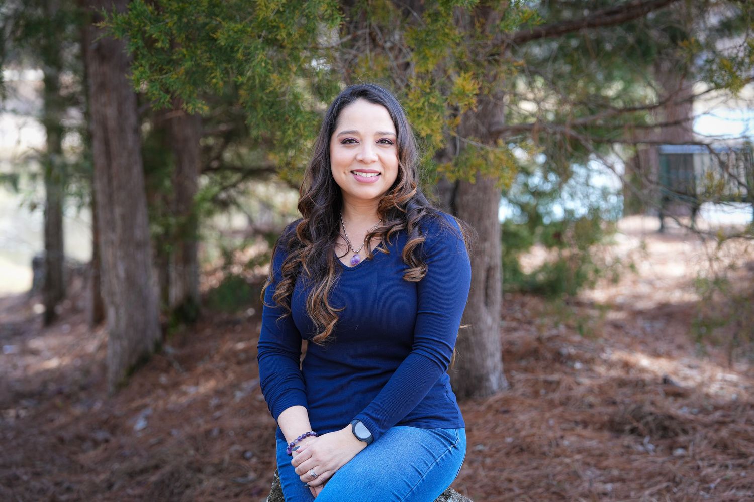 A person in a bright blue top poses outdoors against a natural wooded background in a series of casual portraits.