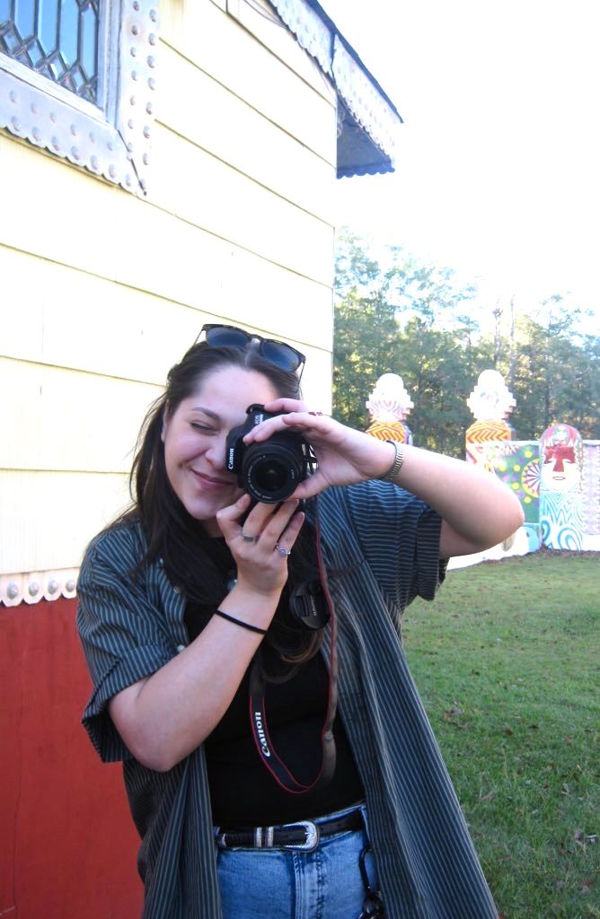 A photographer takes photos from different angles while holding a DSLR camera outdoors.