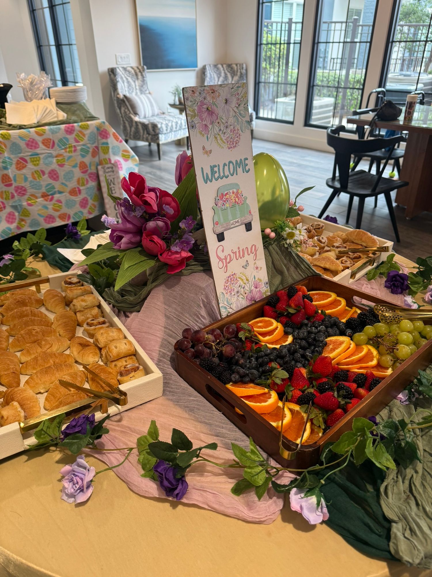 Spring welcome table display with fresh fruit platter, pastries, and floral decorations at a seasonal party.