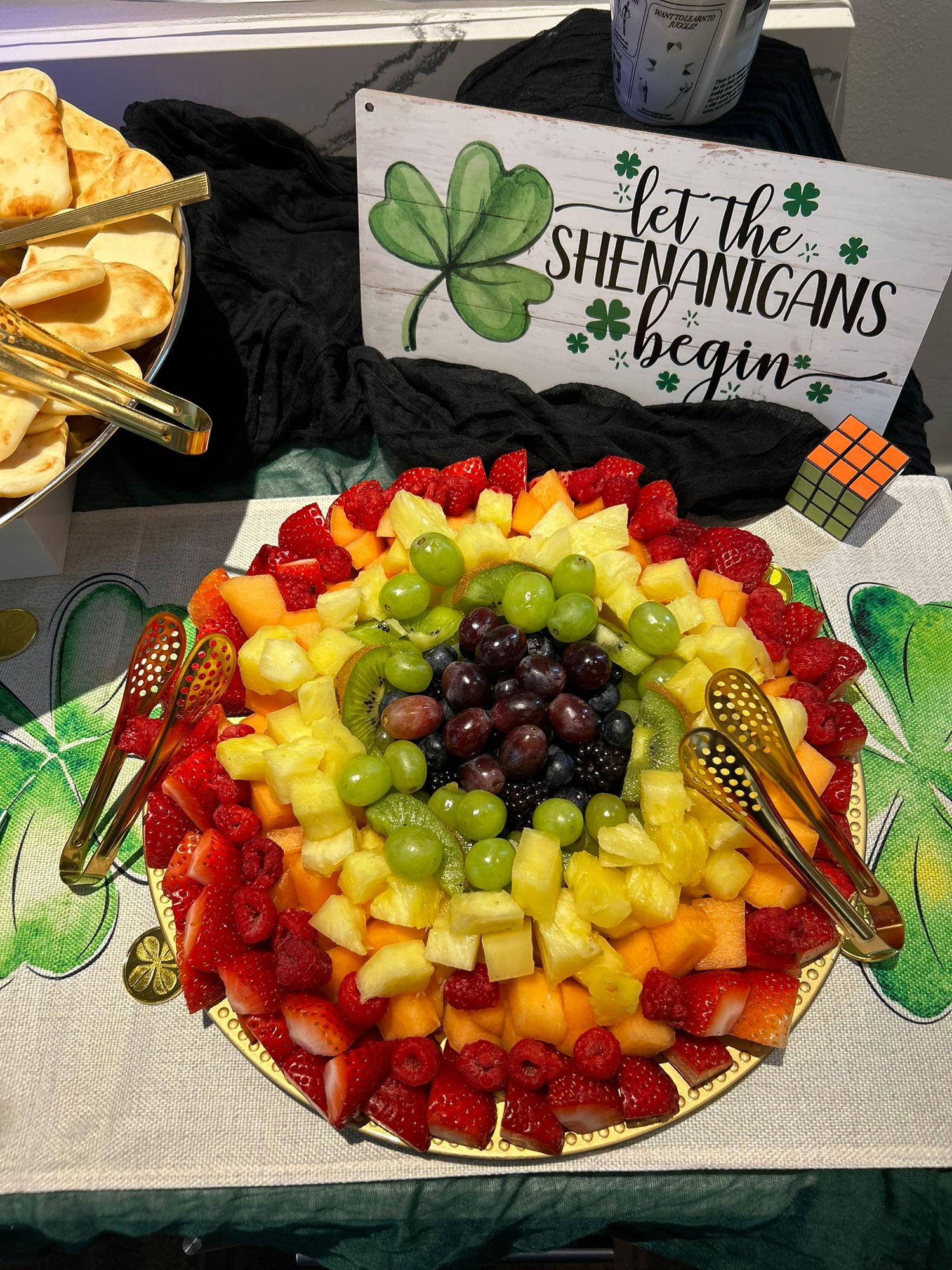 Colorful rainbow fruit platter with strawberries, grapes, and pineapple at a St. Patrick's Day party.