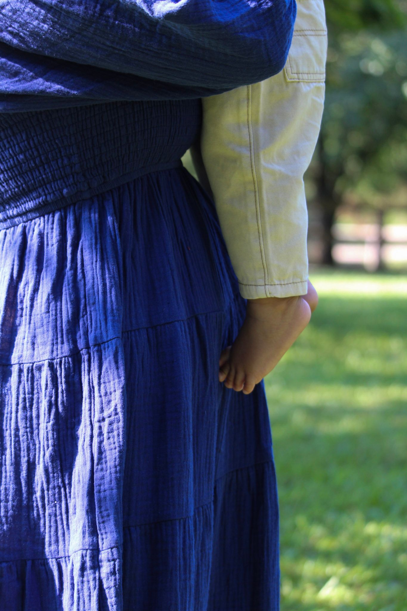 Close-up detail of a navy blue dress fabric against a blurred green outdoor background.