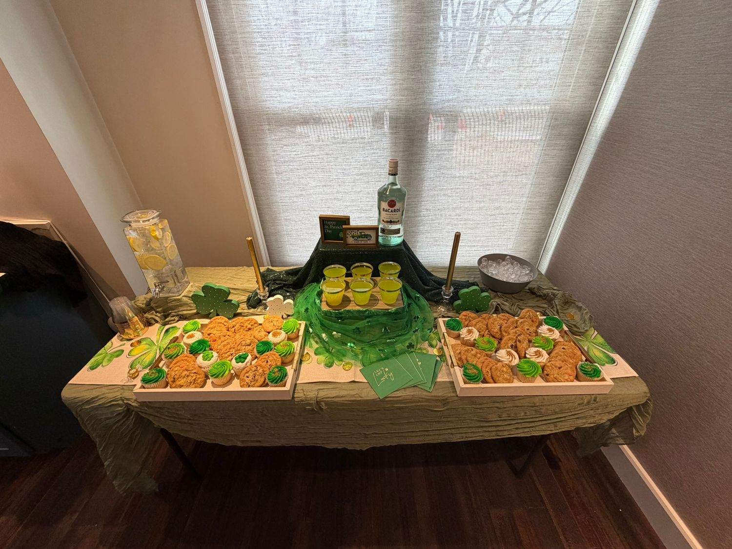 St. Patrick's Day party food table with orange appetizers, green decorations, and a bottle of Tito's vodka.
