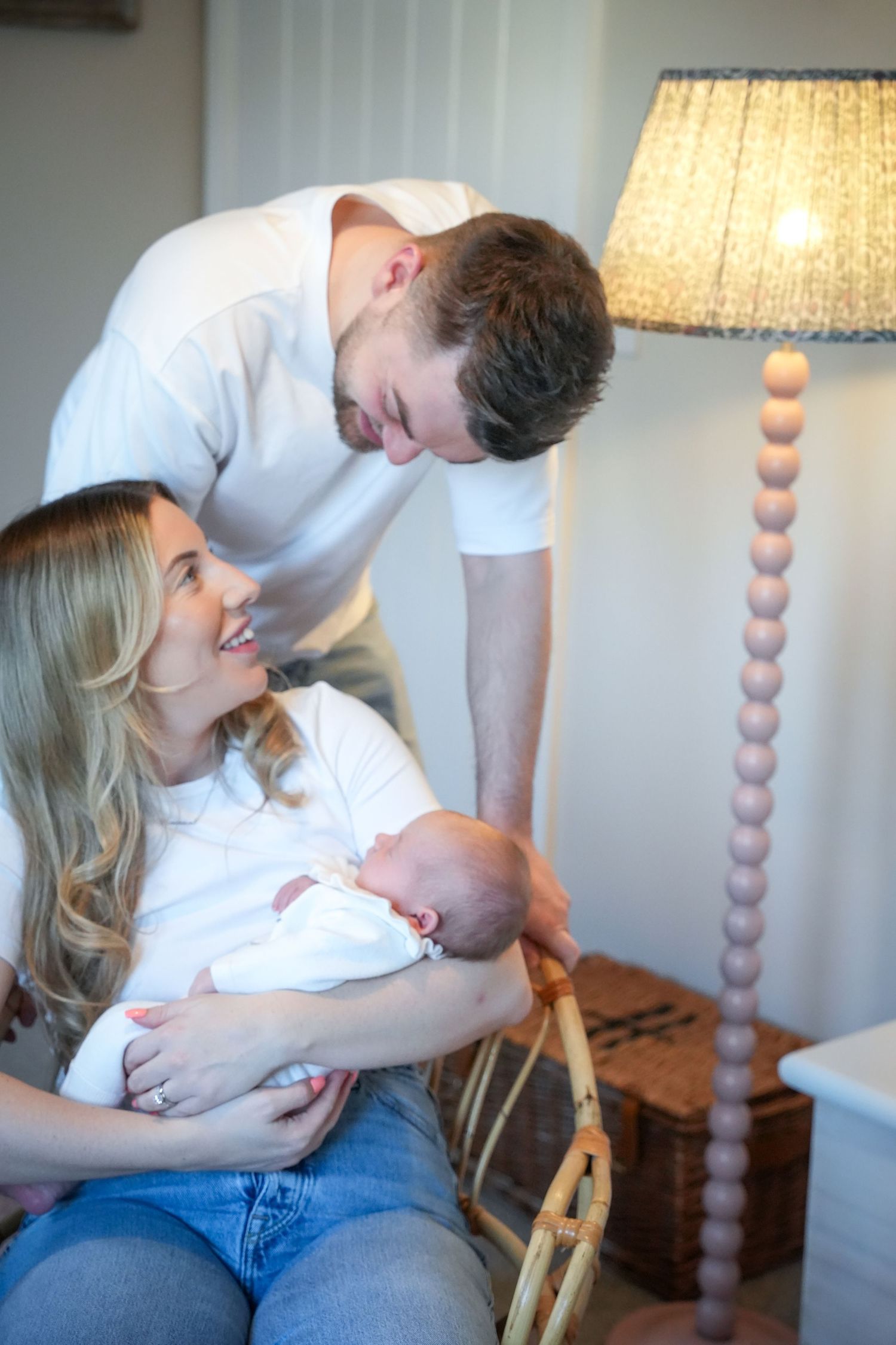 Photo of mum, dad and baby at home relaxed, light, airy background with natural lighting