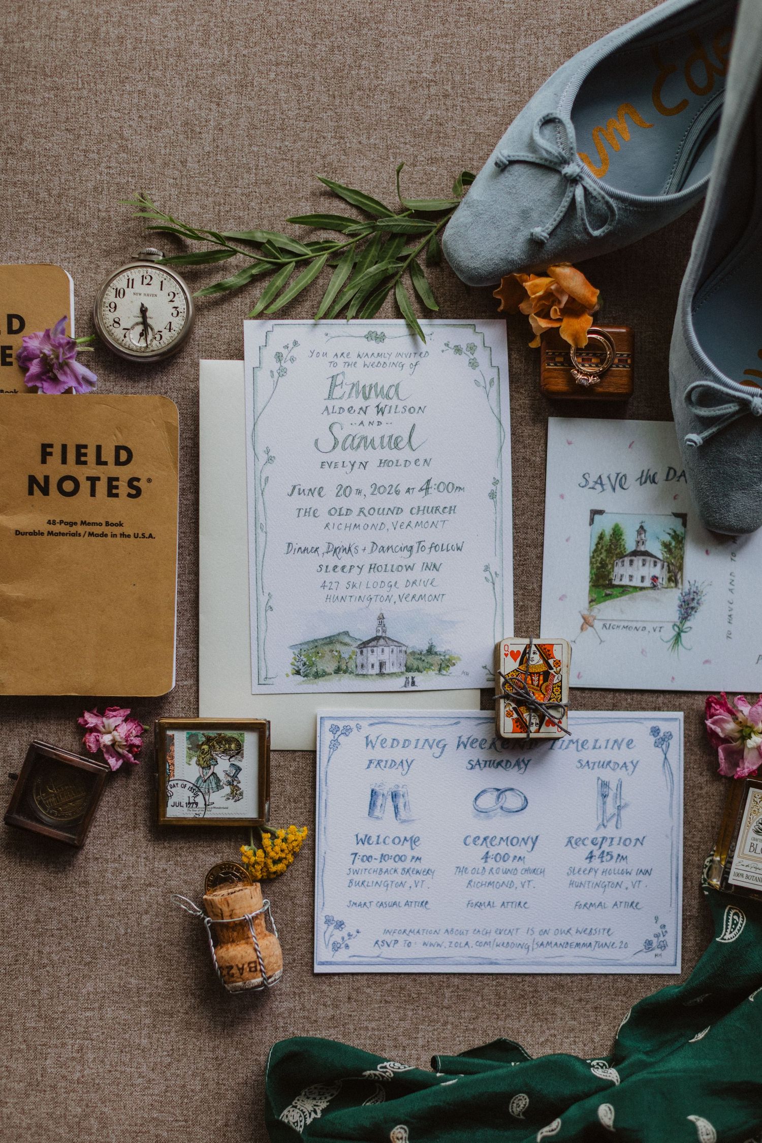 Elegant wedding invitation suite with field notes, vintage clock, blue suede shoes, floral accents, and illustrated venue card on linen.