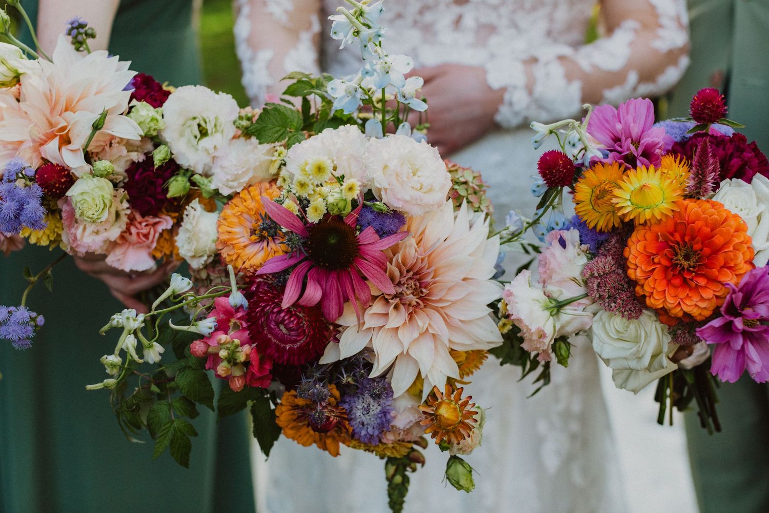 Colorful wedding bouquets featuring dahlias, zinnias, and wildflowers held by bride and bridesmaids.