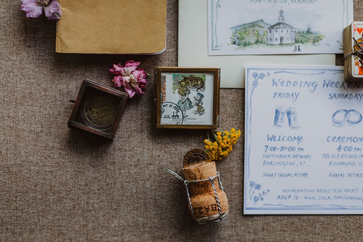 Elegant wedding stationery flat lay with watercolor invitations, vintage ring box, dried flowers, and cork on linen.