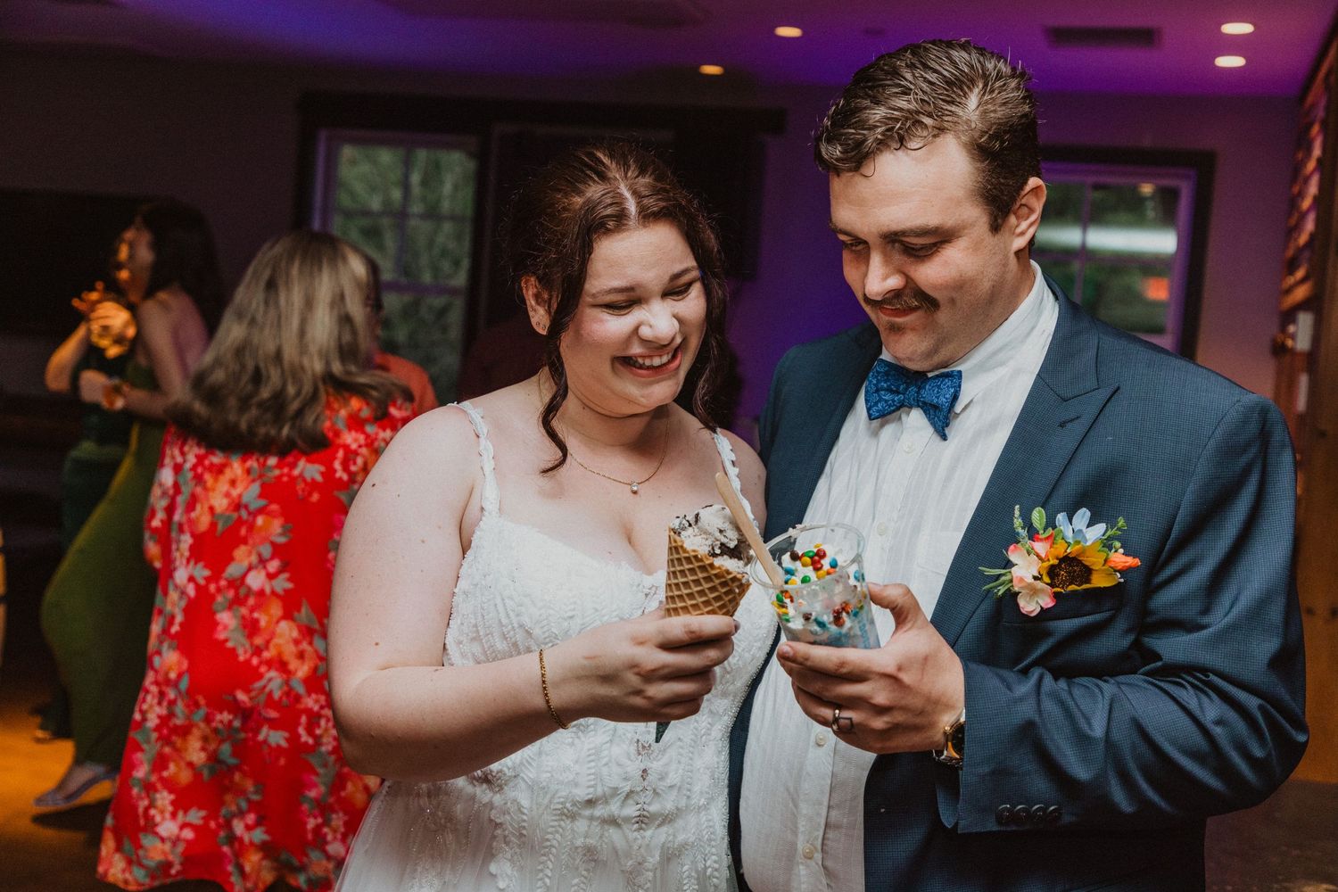 Bride and groom smiling while enjoying ice cream cones together at their wedding reception.