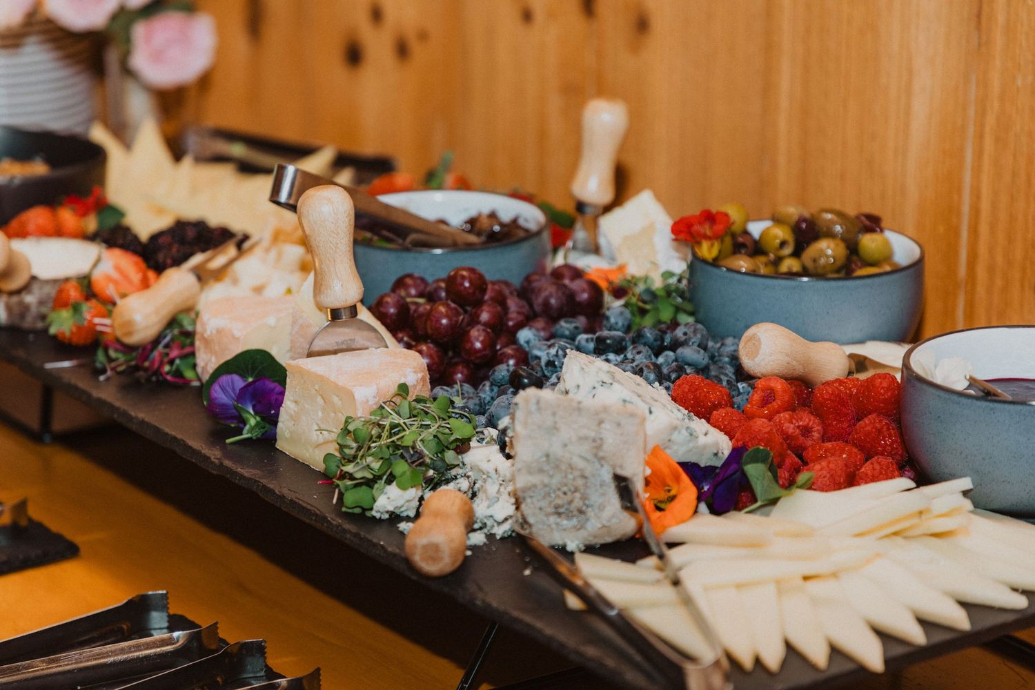 Elegant wedding charcuterie board with assorted cheeses, grapes, strawberries, olives, and gourmet accompaniments.