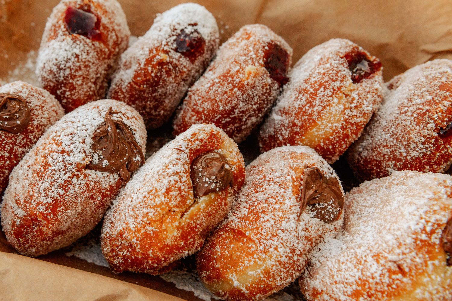 Berliner donuts filled with raspberry jam and Nutella, rolled in granulated sugar and sprinkled with powdered sugar