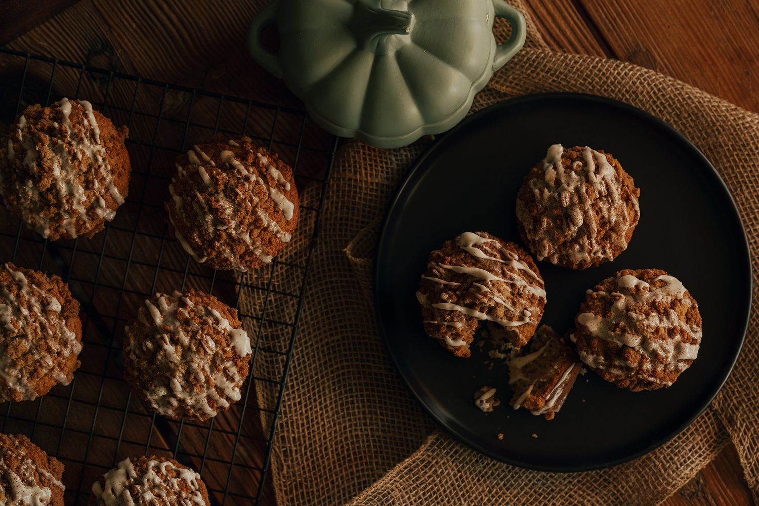 Freshly baked glazed muffins on a cooling rack and black plate with a decorative pumpkin, perfect for fall baking.