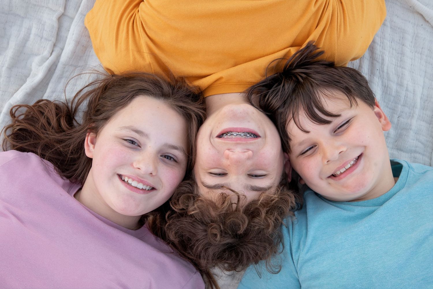 A series of candid overhead shots showing children lying down with their heads together in a circle formation.