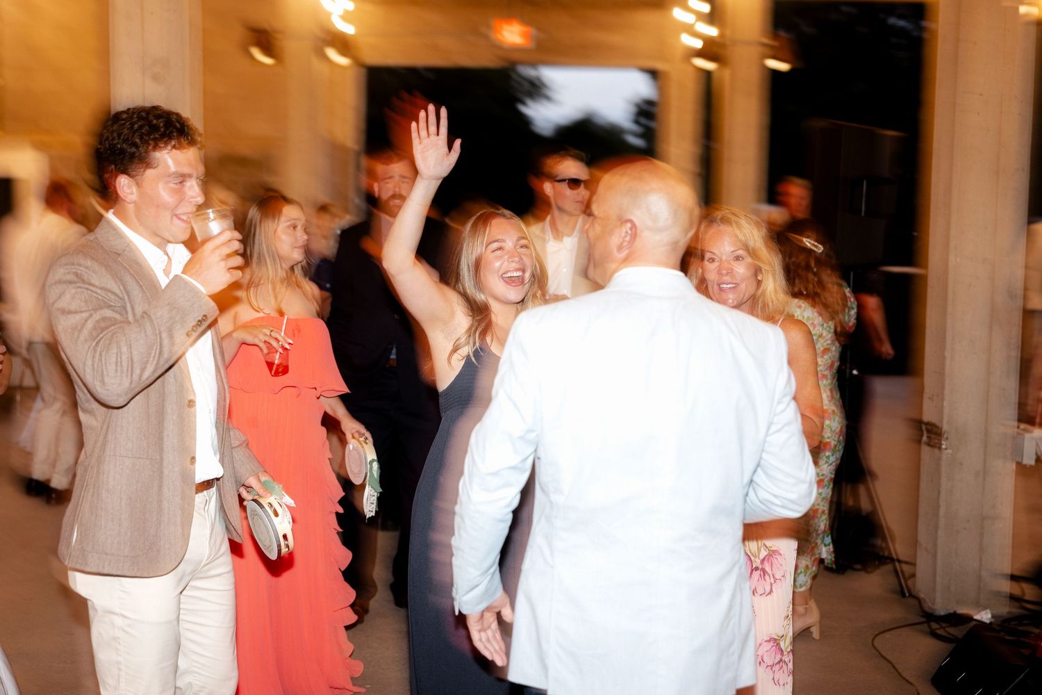 Guests laughing and dancing at an elegant outdoor wedding reception party.