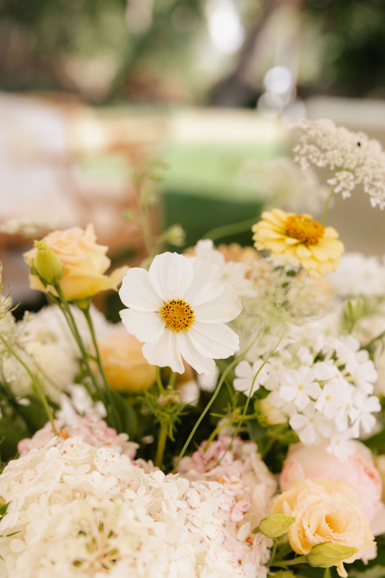 Close-up of romantic wedding centerpiece with white cosmos, peach roses, and hydrangeas.