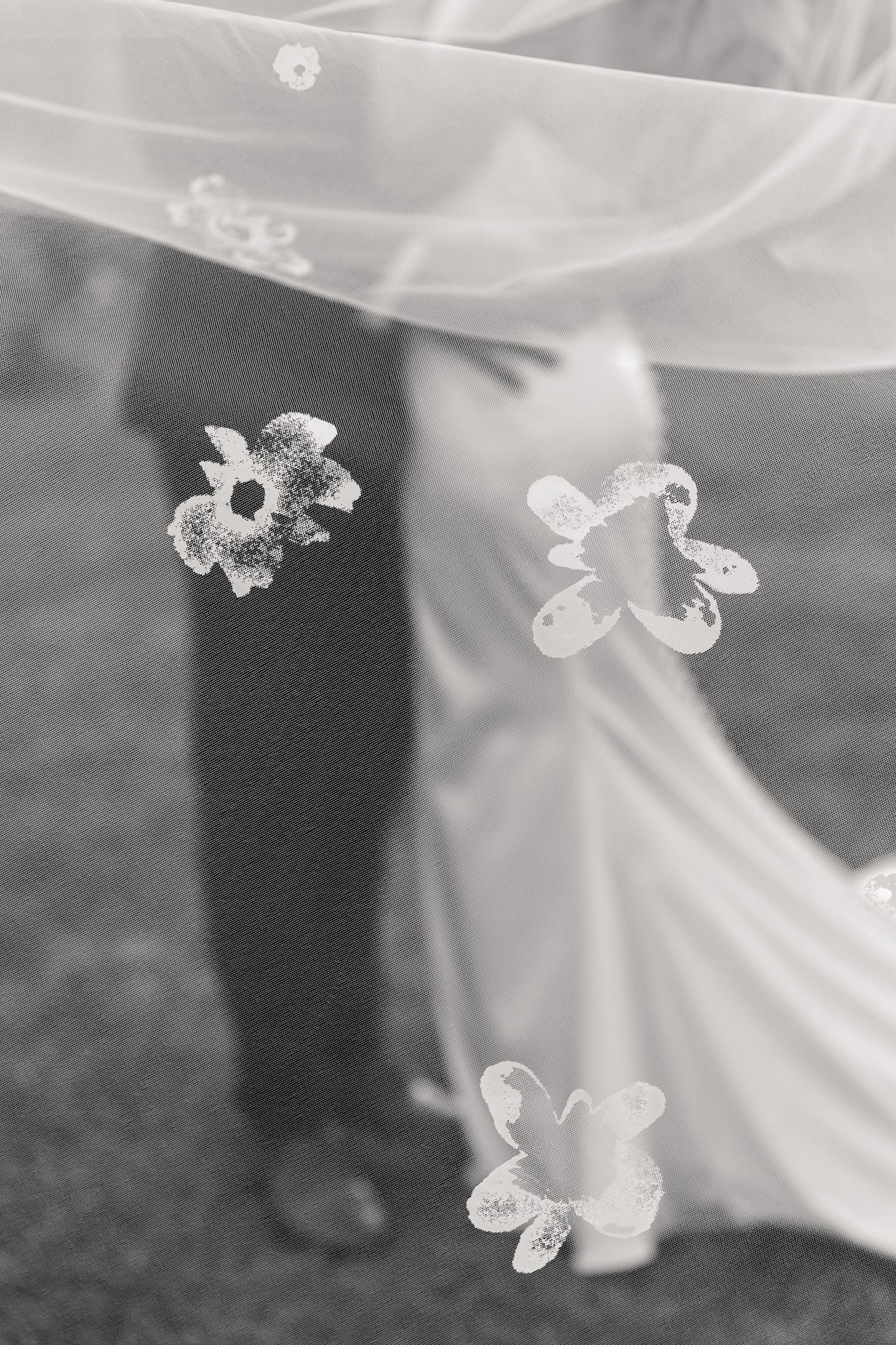 Black and white wedding photo of bride and groom through floral veil.