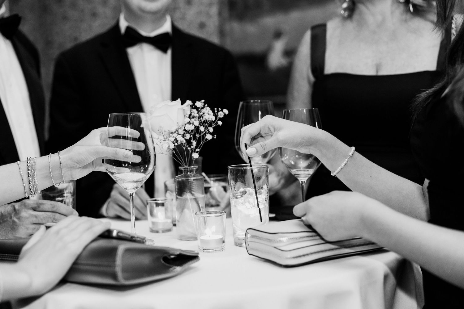 Guests in formal attire toasting champagne glasses at an elegant black and white wedding reception.