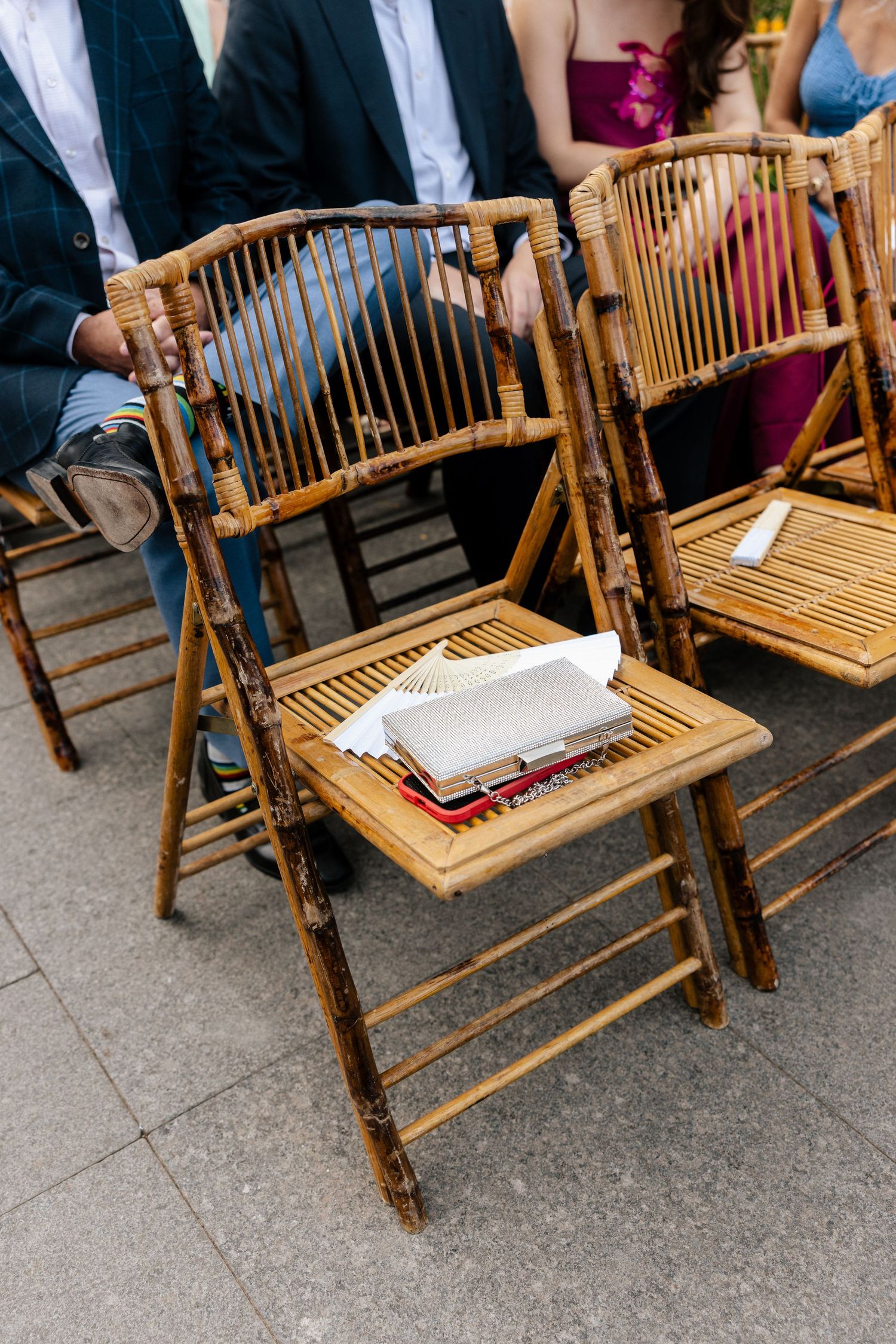 Bamboo folding chairs with wedding programs at outdoor ceremony seating area.