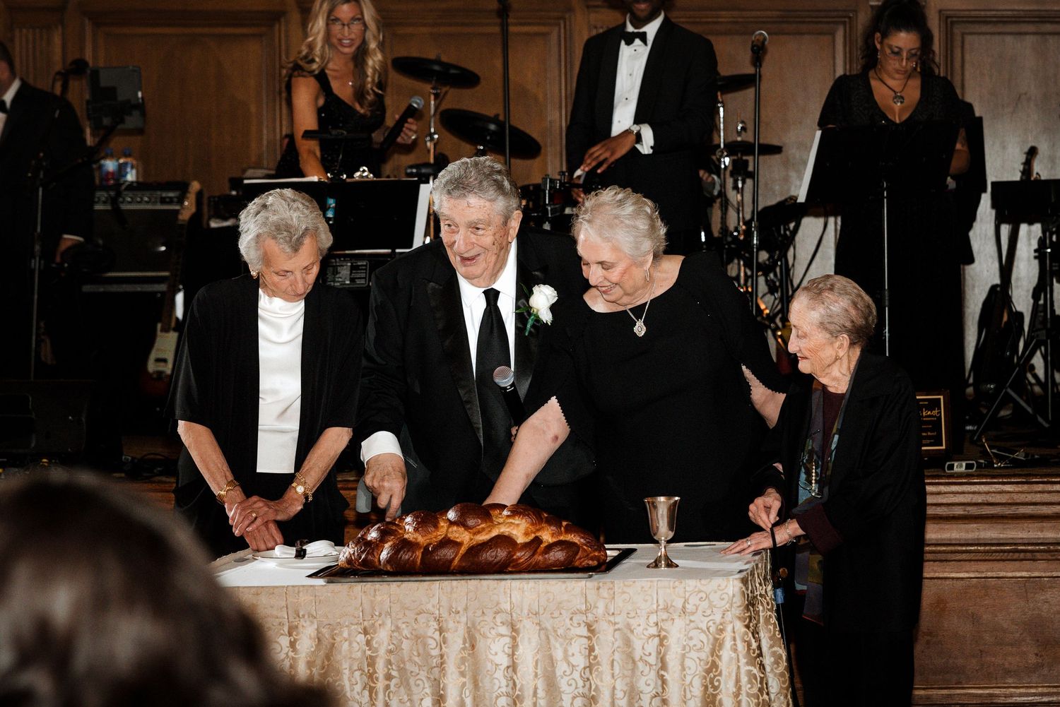 Elderly family members gathered around challah bread for traditional Jewish wedding blessing.