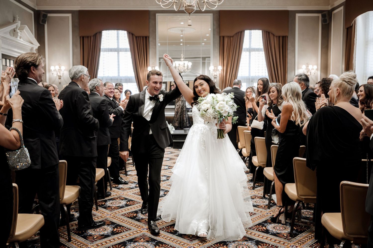 Newlyweds joyfully walk back down the aisle after their wedding ceremony as guests celebrate around them.
