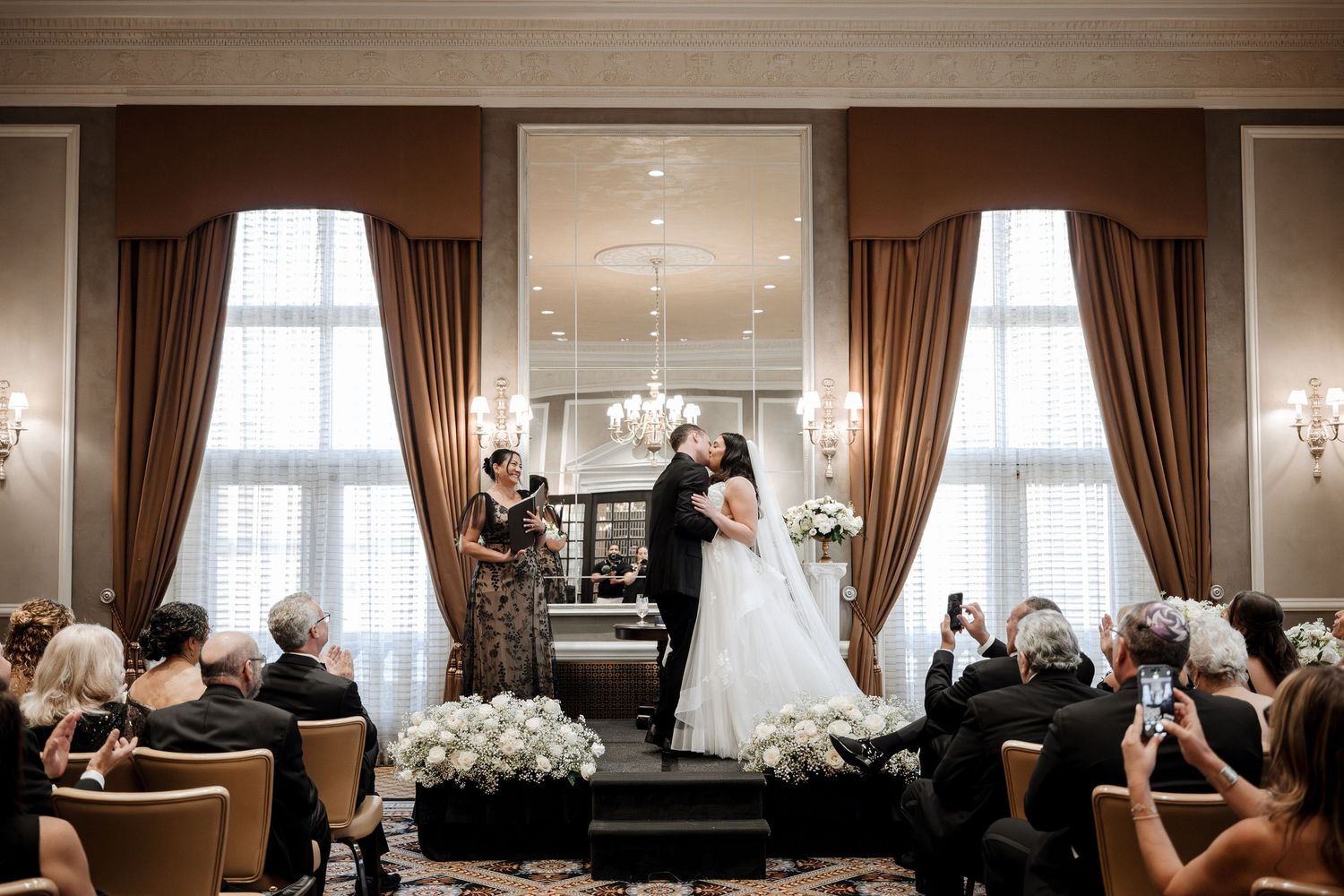 Bride and groom share their first kiss at the altar in a grand ballroom wedding ceremony.