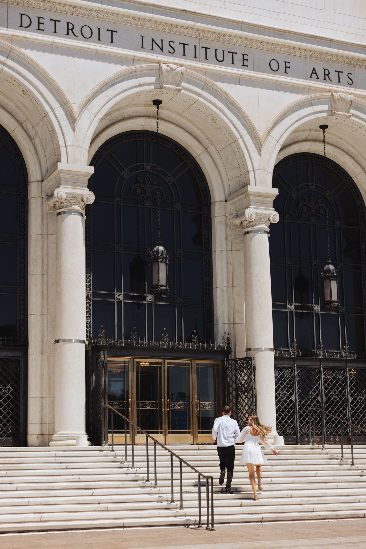 Couple climbing steps to the Detroit Institute of Arts entrance with grand arched columns.