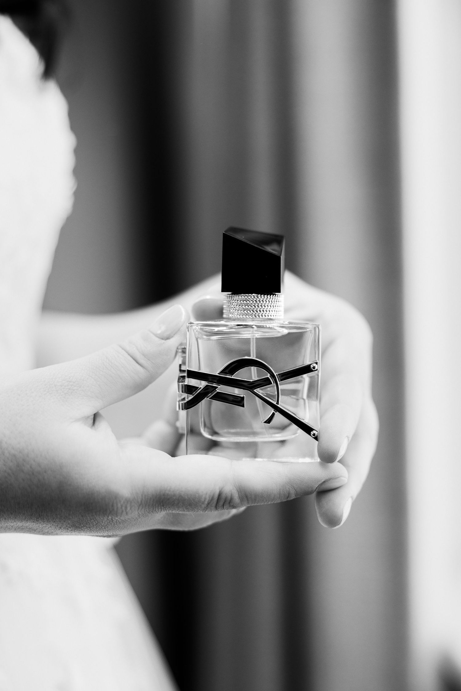 Bride holding YSL Libre perfume bottle in black and white bridal portrait.
