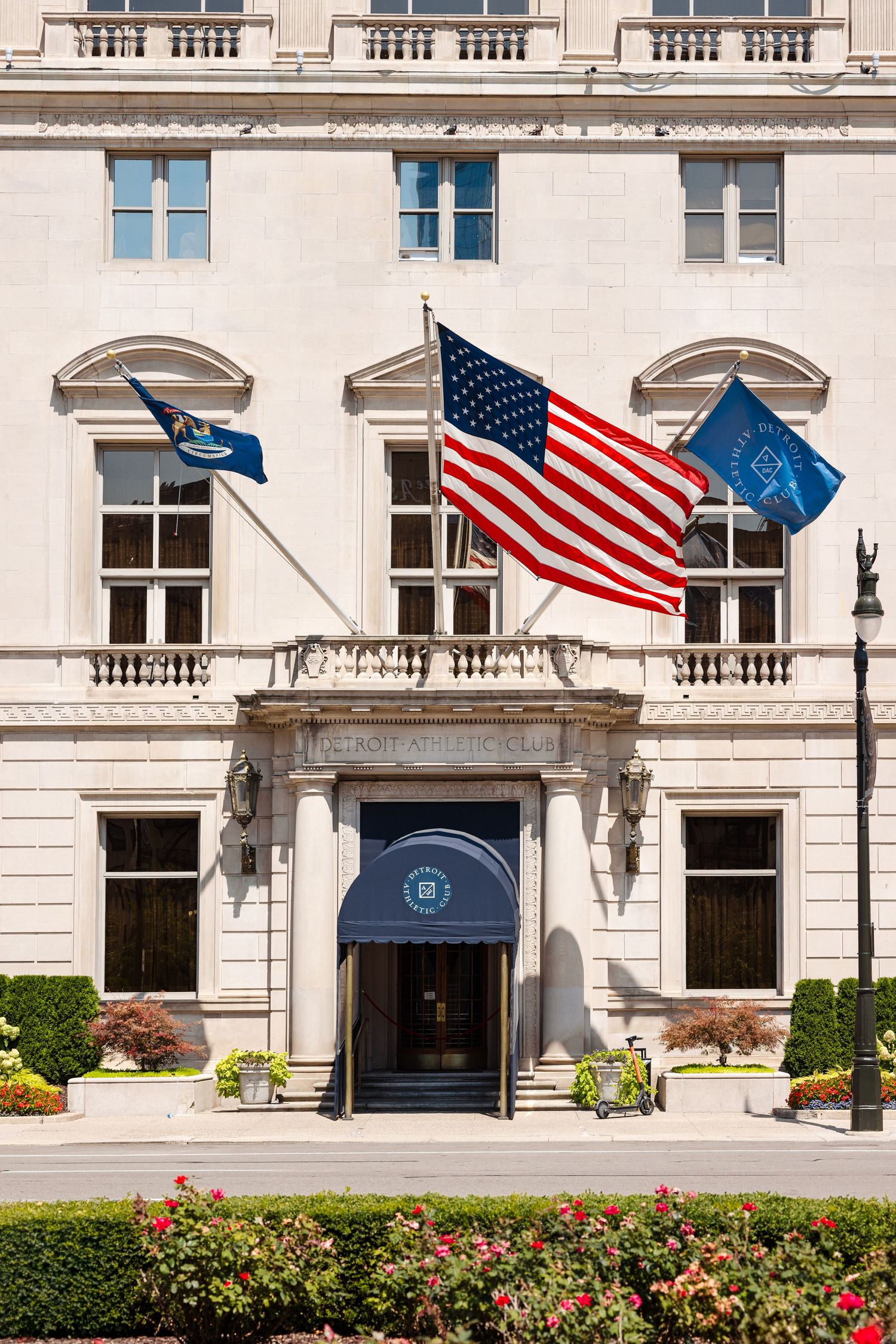 Detroit Athletic Club exterior featuring American flag and state flags flying above the elegant neoclassical entrance.