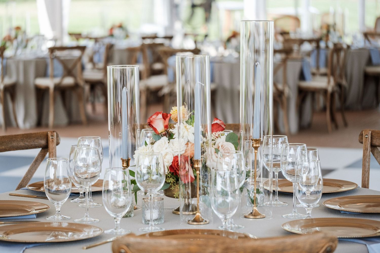 Elegant wedding reception table with floral centerpiece, tall glass vases, and crystal stemware.