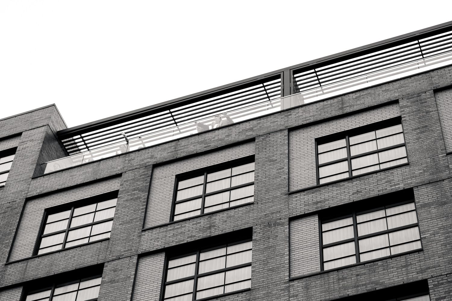 Black and white low angle architectural shot of modern brick building exterior windows.