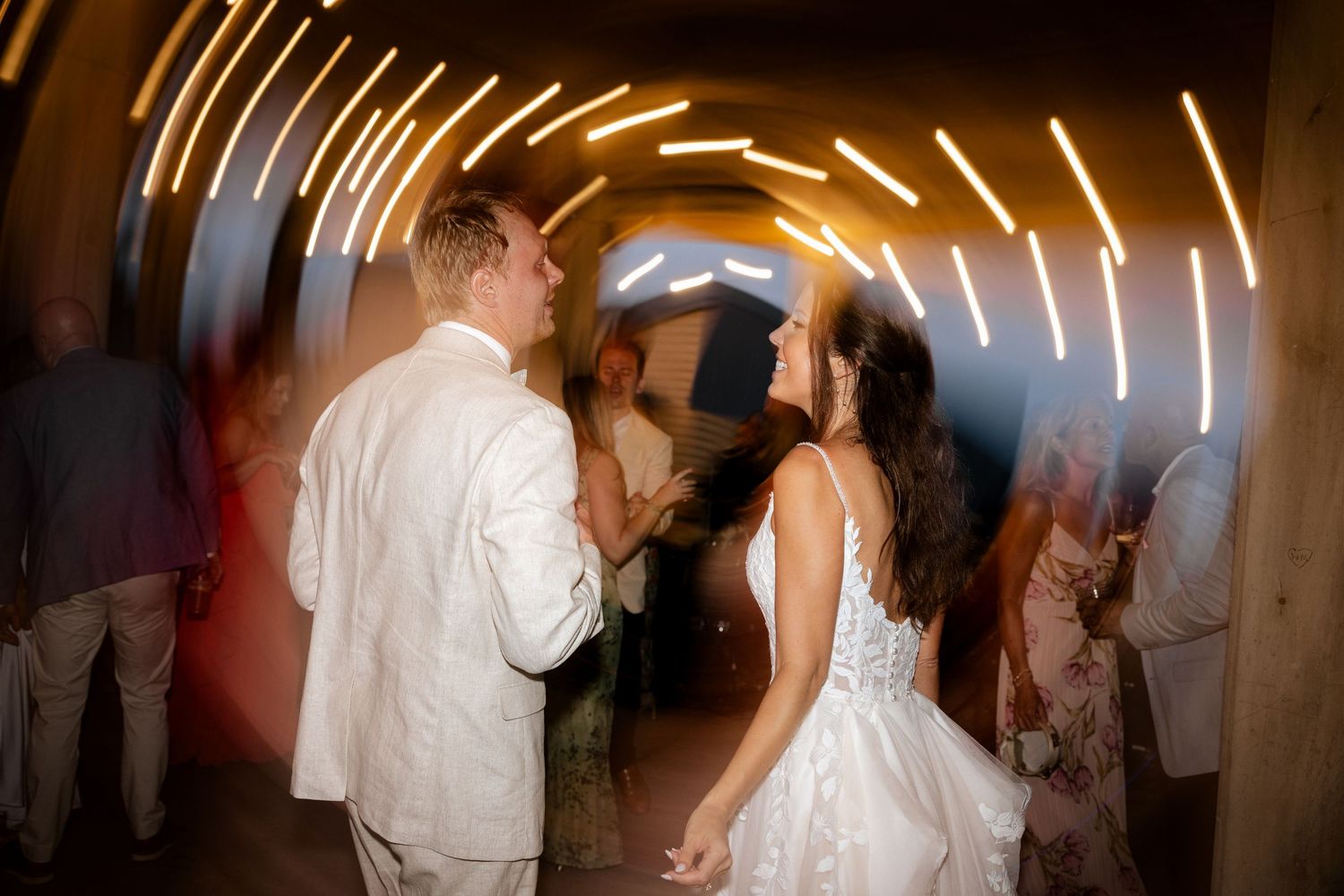 Bride and groom share a romantic first dance under glowing light arch at elegant wedding reception.