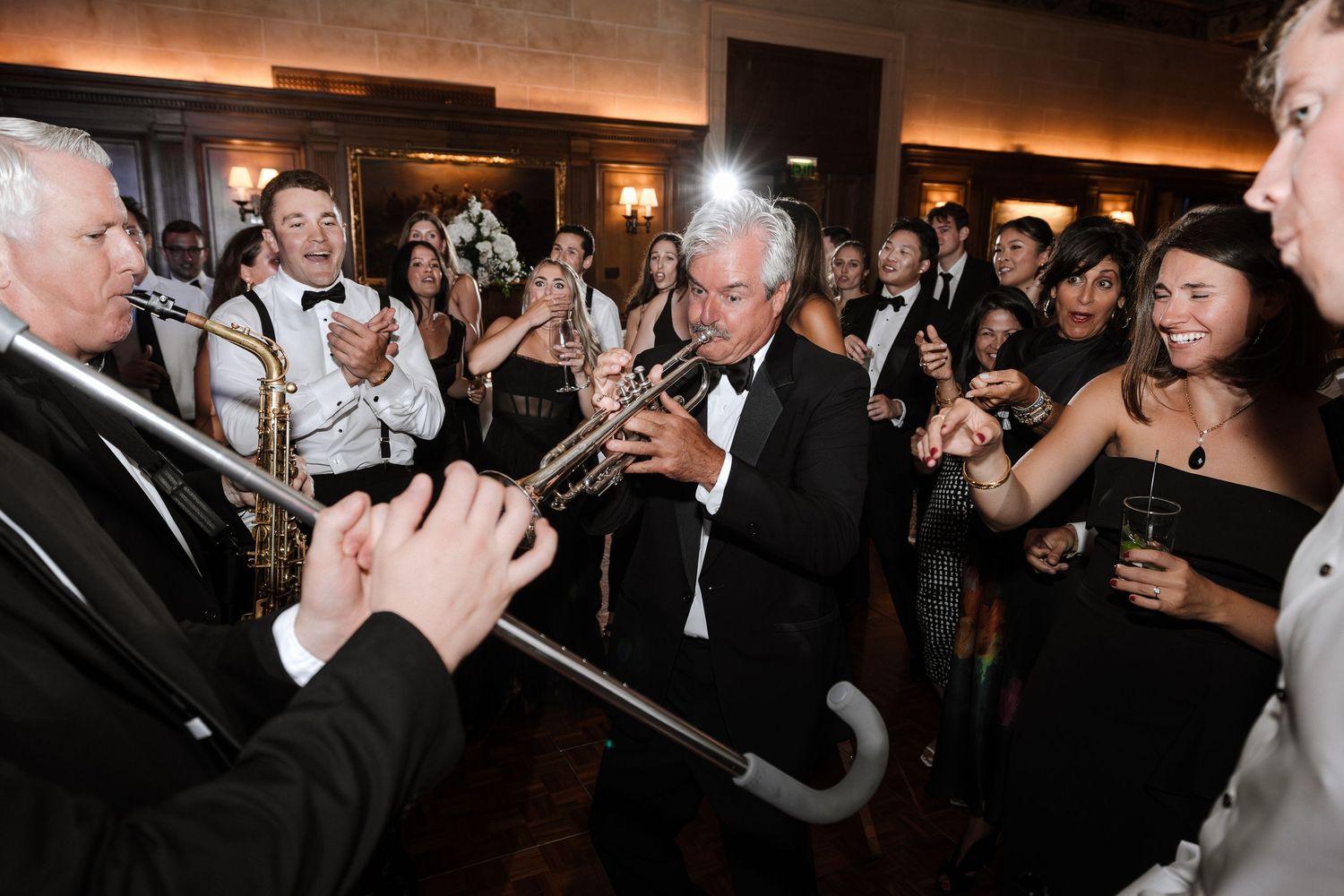 Live trumpet player performs among cheering wedding guests at an elegant reception.