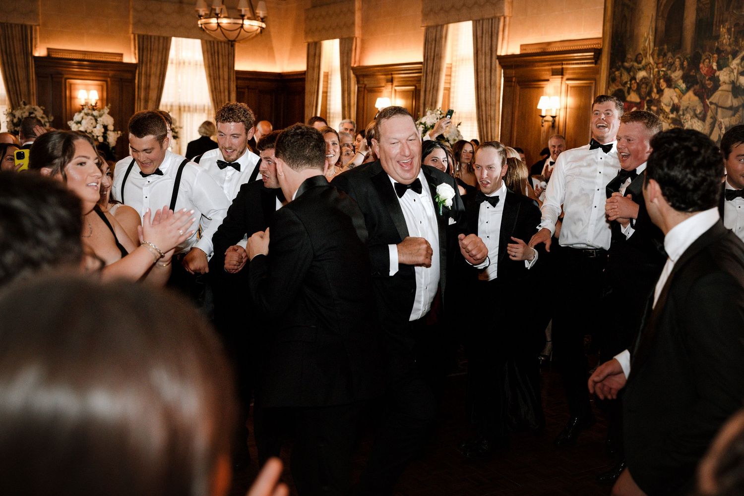 Guests in formal attire dancing joyfully together on elegant wedding reception floor.