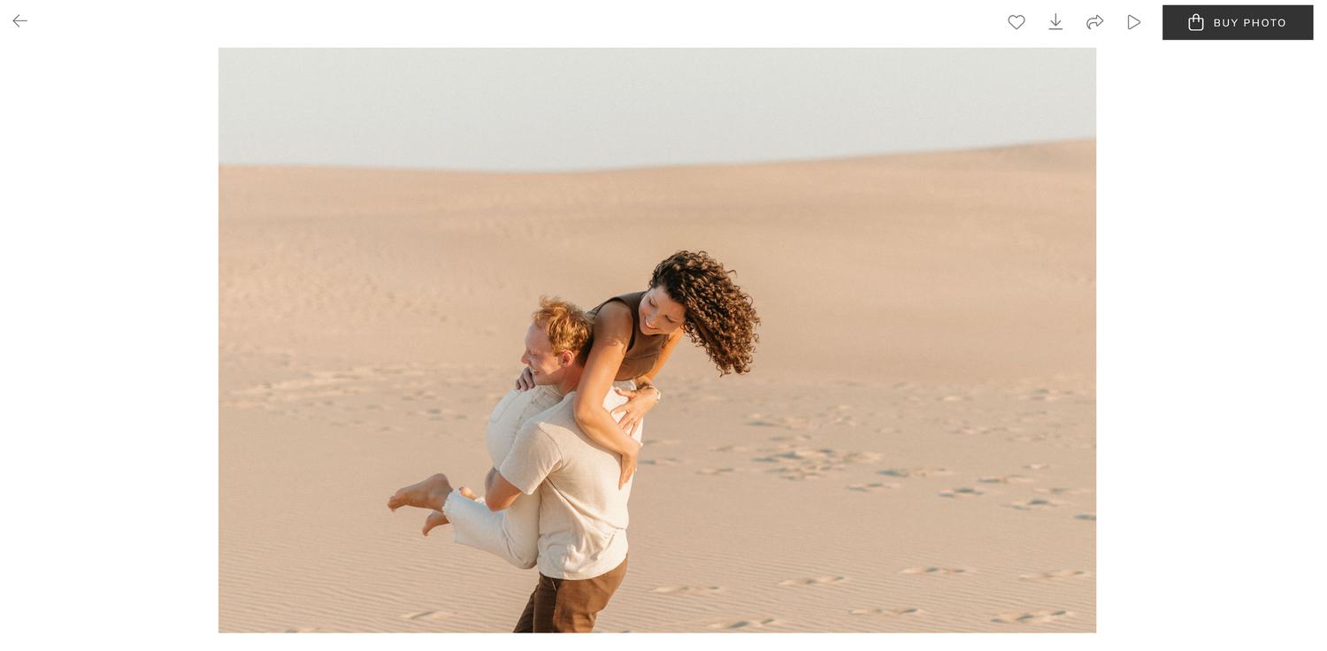 Romantic couple embracing on sandy desert dunes during golden hour engagement session.