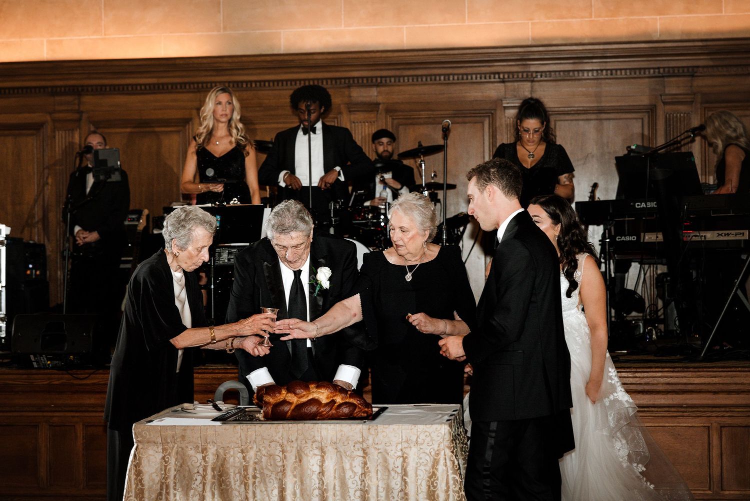 Family members and newlyweds participating in traditional challah blessing at wedding reception.