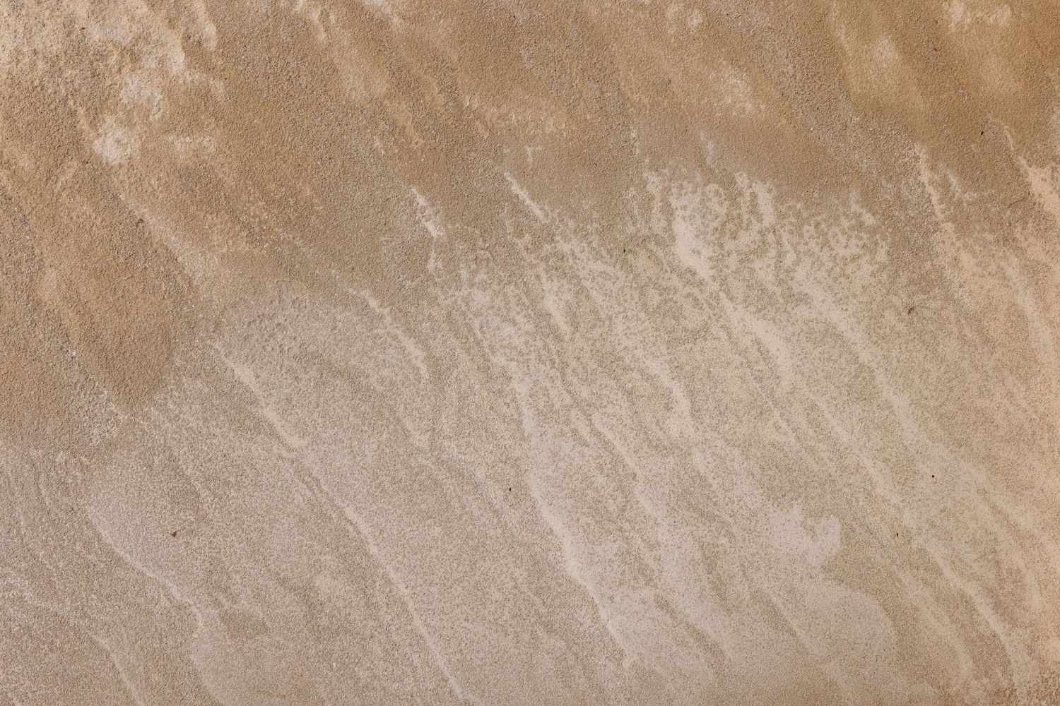 Close-up of a smooth beige sandstone surface with natural streaks and subtle texture variations in warm tan tones.