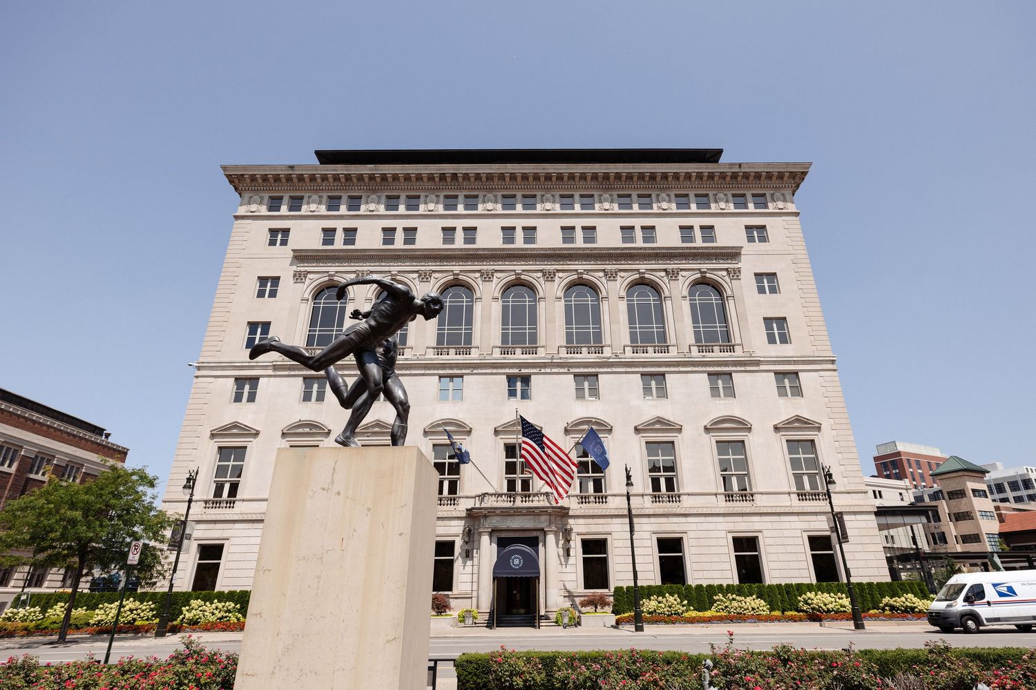 Grand Beaux-Arts Detroit Athletic Club building exterior with bronze runner statue and American flag.