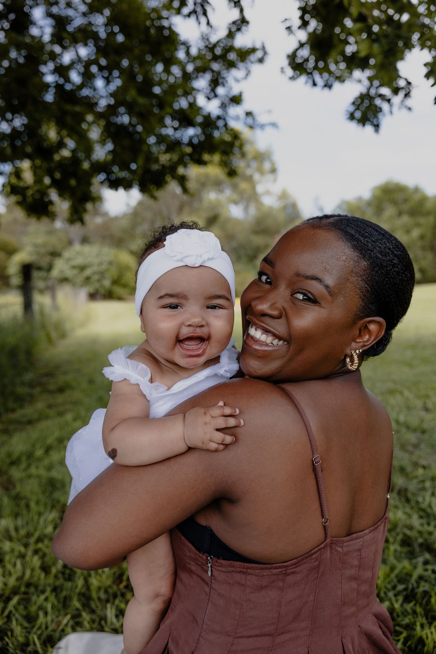 baby in mums arms, both mum and baby looking at camera laughing