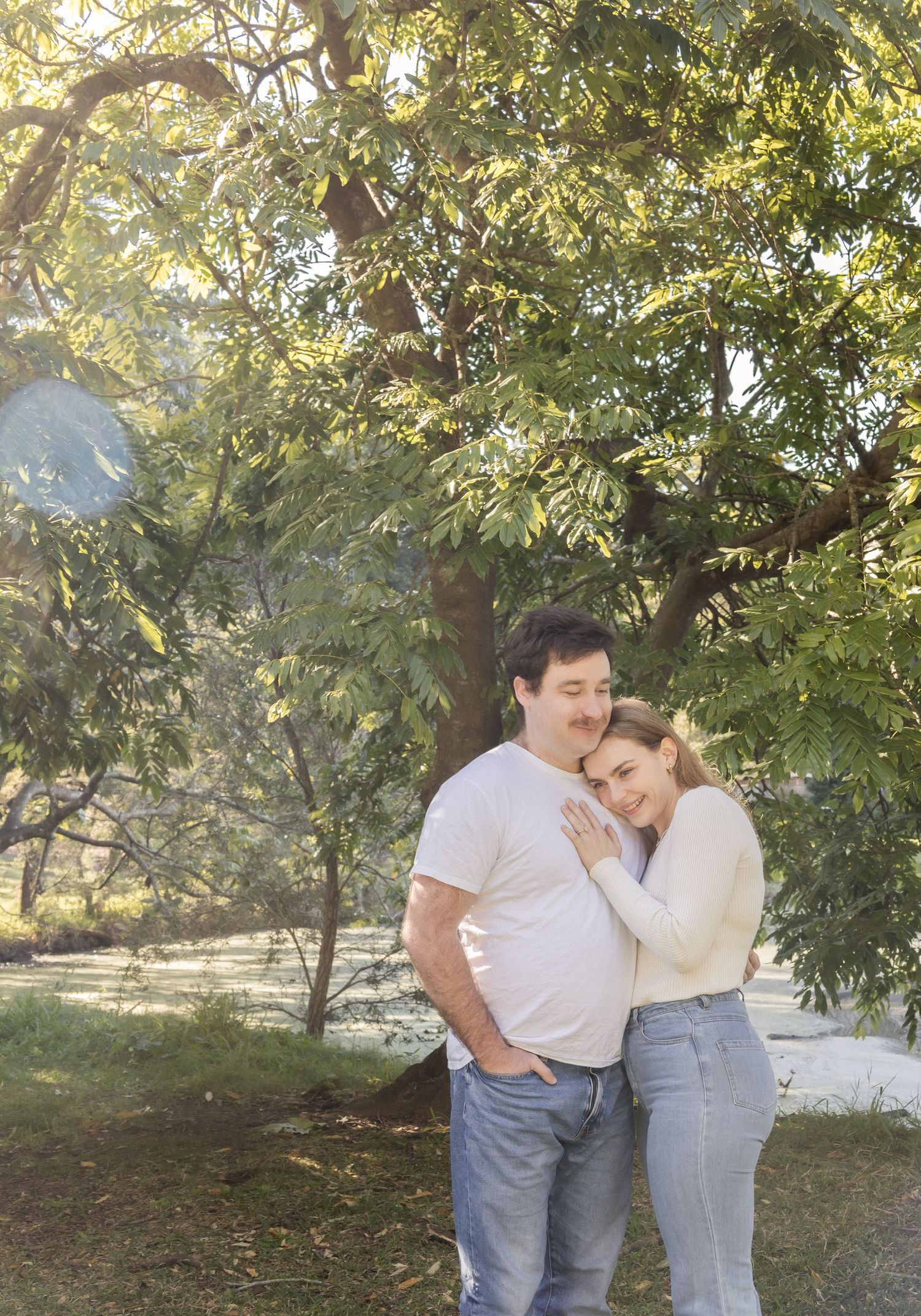 couple holding eachother with lush greenery behind