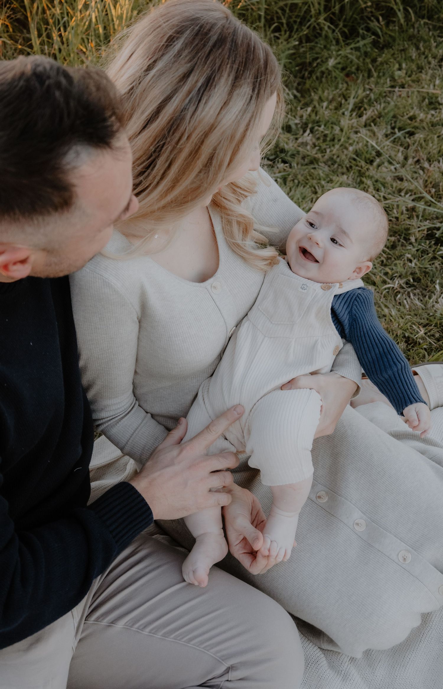 baby in mums arms with dad over the shoulder