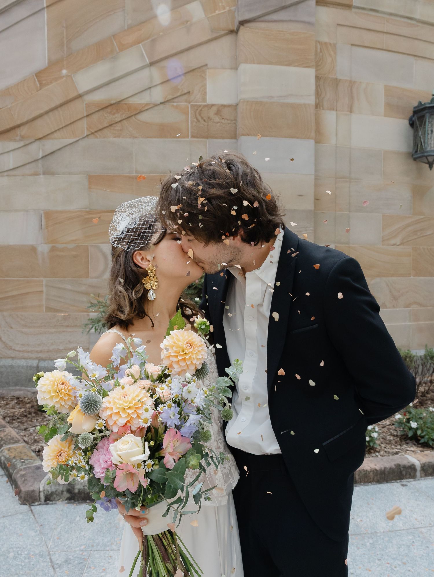 couple kissing. Bridal holding bouquet of flowers and confetti in the air